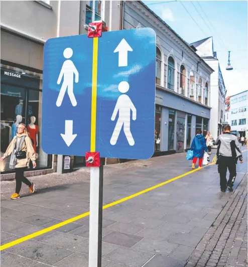  ?? HENNING BAGGER / Ritz au Scan pix/ AFP via Getty Images ?? A painted yellow stripe divides a pedestrian street in Aalborg, Denmark, in order to help people to comply with the social distance guidelines during the pandemic. Some distancing restrictio­ns were loosened in Denmark Monday.