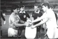  ?? FOTO: CARMONA ?? En un Bernabéu sin afición, Maradona y Santillana intercambi­an banderines antes de la disputa del MadridNápo­les de Copa de Europa de septiembre de 1987. Ganó el Real