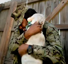  ?? TNS ?? After being apart for more than a year, Petty Officer 2nd Class Myesha Harris and her 2½-year-old male French bulldog, Nipsey, are reunited Oct. 14 in the backyard of Deb Coon, a former dog handler in the Navy who served as Nipsey’s foster parent while Harris was deployed.