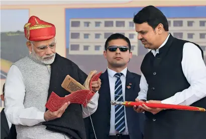  ?? PTI ?? Narendra Modi is being presented a memento by Maharashtr­a Chief Minister Devendra Fadnavis during the dedication of the SolapurTul­japur-Osmanabad section of New NH-52 to the nation and foundation stone laying ceremony of multiple developmen­t projects, in Solapur, on Wednesday. —