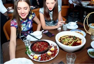  ??  ?? Des Occidental­es s’aventurent à goûter des plats épicés du Sichuan.