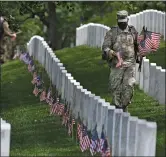  ?? Washington Post photo by Matt McClain ?? Soldiers place flags near headstones at Arlington National Cemetery in advance for Memorial Day on Thursday.