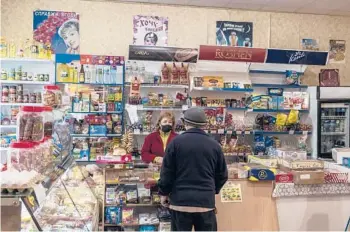  ?? BRENDAN HOFFMAN/THE NEW YORK TIMES ?? Olga Kotesova serves a customer Nov. 5 at her small shop in Hranitne, Ukraine.