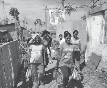  ?? MATTHEW FISHER/POSTMEDIA NEWS ?? Olotayan islanders return from church with bottles of drinking water and a small amount of rice and other staples paid for by Filipinos in Canada, the U.S. and Australia. It is the first relief aid to reach them since Typhoon Haiyan hit on Nov. 8.