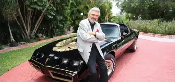  ?? — Courtesy Julien’s Auctions/Reuters photo ?? Reynolds stands next to a 1979 Pontiac Trans Am.