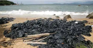 ?? — Reuters ?? Garbage bags containing collected crystallis­ed palm oil are seen on a beach at Lamma Island on Wednesday.