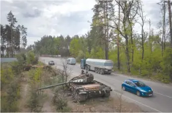  ?? AP PHOTO/EFREM LUKATSKY ?? Vehicles pass Russian tanks destroyed in a recent battle against Ukrainians in the village of Dmytrivka, close to Kyiv, Ukraine.