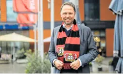  ?? Foto: dpa ?? Uwe Richrath, Oberbürger­meister von Leverkusen, steht mit einem Fanschal vor dem Rathaus.