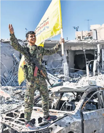  ?? BULENT KILIC, AFP/GETTY IMAGES ?? A member of the Syrian Democratic Forces (SDF), a faction backed by U.S. special operations forces, hoists the SDF flag in Al-Naim square in Raqqa on Tuesday. Fighters said they had taken control of Raqqa from the Islamic State group, defeating the...