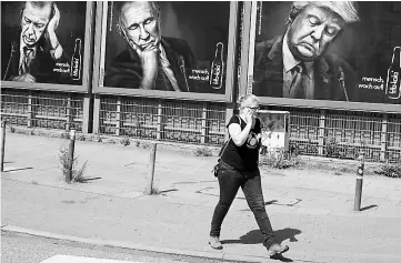  ??  ?? A woman walks past advertisin­g posters of a German soft drink producer depicting Turkey’s President Tayyip Erdogan, Russian President Vladimir Putin and US President Donald Trump during the G20 summit in Hamburg, Germany, July 6. — Reuters photo