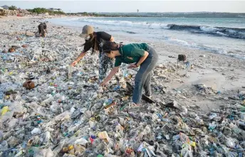 ?? — AFP photo by Sonny Tumbelaka ?? People look through plastic and other debris washed ashore at Kedonganan Beach near Denpasar on Indonesia’s resort island of Bali.