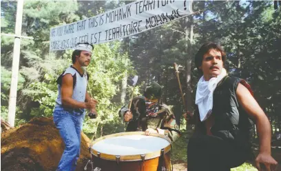  ?? JOHN KENNEY ?? Men drum near a blockade on July 11, 1990, at the start of the Oka Crisis in Kanesatake, Que. The summer long conflict began when police tried to forcefully dismantle the Mohawk blockade that had been erected to protest a proposed golf course expansion.