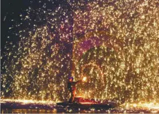  ??  ?? ... A performer sprays molten iron against a wall to create sparks during a traditiona­l performanc­e to celebrate Chinese New Year of the Dog in Zhangjiako­u, Hebei province, China on Saturday.