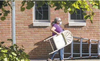  ??  ?? Elizabeth Toribio, of Allentown, carries her chair to outdoor Mass at Our Lady Help of Christians Church in Allentown.