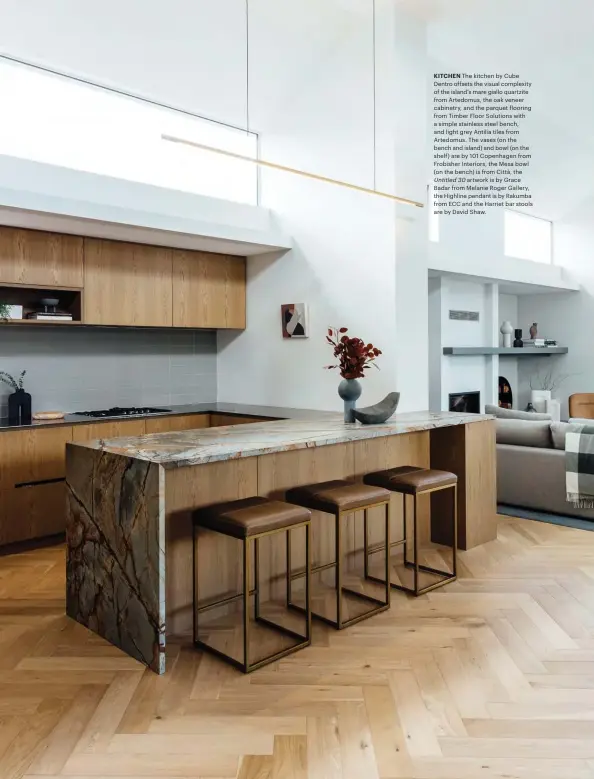  ??  ?? KITCHEN The kitchen by Cube Dentro offsets the visual complexity of the island’s mare giallo quartzite from Artedomus, the oak veneer cabinetry, and the parquet flooring from Timber Floor Solutions with a simple stainless steel bench, and light grey Antilia tiles from Artedomus. The vases (on the bench and island) and bowl (on the shelf) are by 101 Copenhagen from Frobisher Interiors, the Mesa bowl (on the bench) is from Città, the Untitled 30 artwork is by Grace Badar from Melanie Roger Gallery, the Highline pendant is by Rakumba from ECC and the Harriet bar stools are by David Shaw.