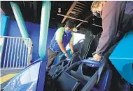  ?? K.C. ALFRED U-T ?? SeaWorld San Diego workers Martin Lopez and Katie Byle check seat restraints on the Electric Eel coaster for a test run on Thursday. More rides there will open Monday.