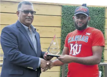  ?? (Photo: Garfield Robinson) ?? Groom Steven Smith (right) receives his championsh­ip trophy from Racing Secretary Denzil Miller at the races on Saturday, February 24, 2024.