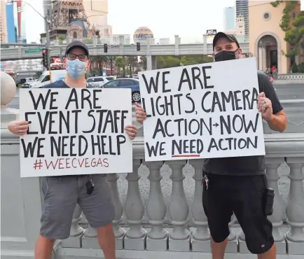  ?? ETHAN MILLER/GETTY IMAGES ?? Performer Marc Roberts, left, from Blue Man Group at Luxor Hotel and Casino and Blue Man Group lighting maintenanc­e technician Adam Bergeron hold signs during a “Drive and March” event held by We...The Entertainm­ent Community of Las Vegas (WE/EC) down the Las Vegas Strip in support of the Las Vegas entertainm­ent industry.