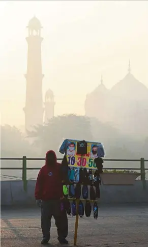  ?? — AFP ?? Toxic air: a vendor selling masks amid heavy smog in Lahore.