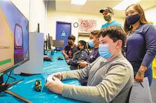  ?? SANDY HUFFAKER ?? Elyana Delgado and coach Michael Norton watch Ronnie Tovar, 13, Christophe­r Castillo, 13, Emanuel Beltran Pelaez, 12, and Josve Beltran, 13, play esports at Casa de Salud on Wednesday.