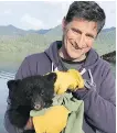  ?? THE CANADIAN PRESS ?? John Forde holds an orphaned black bear cub near Tofino, B.C.