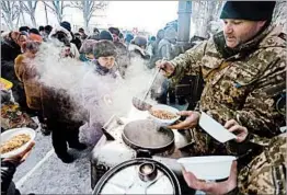  ?? FILIPPOVAL­EKSEY/AFP-GETTY ?? Aid workers serve food Monday in Avdiikva, Ukraine, where fighting has flared.