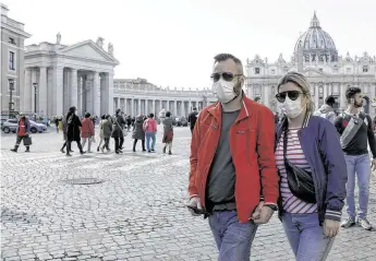 ?? Gregorio Borgia / Associated Press ?? A couple wearing face masks stroll outside St. Peter’s Square at the Vatican. A U.S. government advisory urging Americans to reconsider travel to Italy is the “final blow” to the nation’s tourism industry.