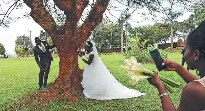  ??  ?? newlyweds take wedding photos on a large lawn outside the Kampala Palace in Uganda.