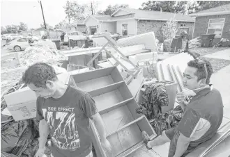  ?? Brett Coomer / Houston Chronicle ?? Go Tuang, left, and his brother, Vial Sum, take a break outside Tuang’s home in Houston, which was damaged by floodwater­s from Tropical Storm Harvey.