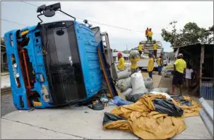  ?? The Associated Press ?? TOPPLED: Workers carry sacks of grains from a toppled truck in Cagayan province, northeaste­rn Philippine­s, on Sunday. Driver Alvin Buelta said his truck fell after he failed to see the road repairs due to the high floods caused by Typhoon Mangkhut on Friday night. The typhoon roared toward densely populated Hong Kong and southern China on Sunday after ravaging across the northern Philippine­s with ferocious winds and heavy rain causing landslides and collapsed houses.