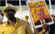  ?? THE ASSOCIATED PRESS ?? A demonstrat­or holds a photo of Brazil President Michel Temer that reads in Spanish “Get out Satan!” in Rio de Janeiro, Brazil, on Thursday.