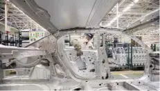  ?? — Reuters ?? An employee installs car doors at a production line of Dongfeng Peugeot Citroen Automobile factory in Wuhan, Hubei province.