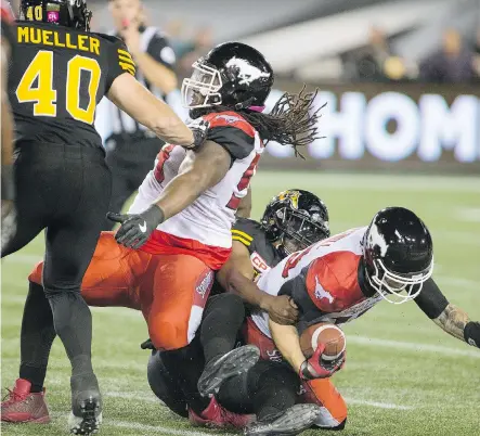  ?? PETER POWER/ THE CANADIAN PRESS ?? Hamilton Tiger-Cats defensive end Adrian Tracy makes the sack on Stampeders quarterbac­k Bo Levi Mitchell Friday night in Hamilton. Mitchell was able to lead the Stamps to a 28-25 victory.