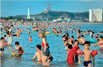  ?? — AFP ?? Local beachgoers enjoy a swim at the Bai Chay beach in Ha Long city of Vietnam on Saturday. The country eased lockdown restrictio­ns and is one of the few nations not to have a single Covid-19 death till date.