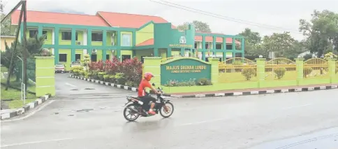  ??  ?? A motorcycli­st passing by Lundu District Office where the flags were still flown half-mast on Monday.