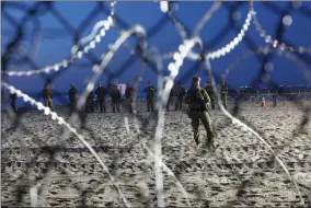  ?? RODRIGO ABD AP PHOTO BY ?? U.S. Border Patrol agents are seen though the border structure from the Mexican side at the Pacific Ocean, Tijuana, Mexico, Friday, Nov. 16. As thousands of migrants in a caravan of Central American asylum-seekers converge on the doorstep of the United States, what they won't find are armed American soldiers standing guard.