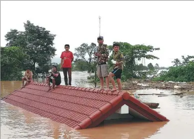  ?? XINHUA ?? Villagers wait to be evacuated after a dam collapsed in Attapeu province, Laos, on Tuesday.