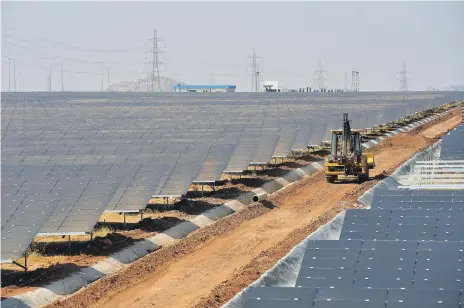  ??  ?? An earth mover amid rows of solar panels at Shakti Sthala, a 2,000MW solar power park in Pavagada Taluk near Bangalore