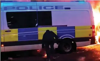  ??  ?? Carnage: A yob in a hooded top sets van alight with police inside on Sunday
