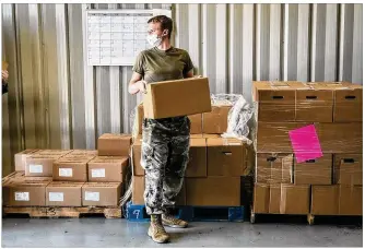  ?? JIM NOELKER / STAFF ?? Ohio National Guardsman Jacob Fisher waits for another car to pull through the Dayton Food Bank drive-thru Monday morning.