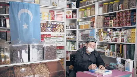  ?? EMRAH GUREL/AP ?? Ahmed Hasim, a member of the Uighur ethnic group, waits for customers Tuesday in his grocery store in Istanbul, Turkey.