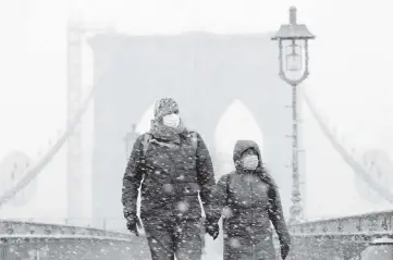  ?? MARK LENNIHAN AP ?? A couple walks on the Brooklyn Bridge on Monday in New York.
