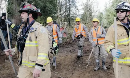  ?? ELAINE THOMPSON/THE ASSOCIATED PRESS ?? Searchers arrive Wednesday to begin a shift at the scene of a deadly mudslide that swept away the small community of Oso, Wash. Officials have so far confirmed the deaths of 29 people.