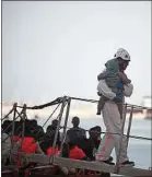  ??  ?? Un bébé secouru en mer est pris en charge par un humanitair­e espagnol.