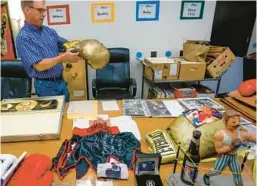  ?? IVY CEBALLO/TAMPA BAY TIMES ?? John Harris, who is an auctioneer, shows boxing memorabili­a once owned by late founder of the Florida Boxing Hall of Fame Walter Flansburg at Alessi Ringside Gym and Fitness in Tampa.