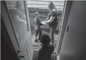  ?? TRIBUNE NEWS SERVICE ?? Kira Meinzer with her twin 5-year-old boys Caden, front, and Reillen Mihelberge­l outside their home, May 29 in Evanston, Illinois.