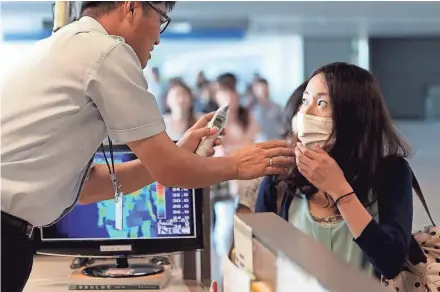  ?? PRESS ASSOCIATED ?? A South Korean quarantine officer (left) checks the body temperatur­e of a passenger on Aug. 8, 2014, at Incheon Internatio­nal Airport in Incheon, South Korea. South Korea stepped up monitoring of its citizens returning from trips to West Africa and...