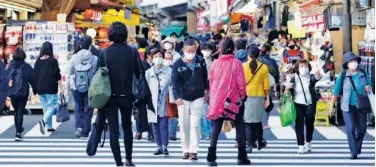  ?? Associated Press ?? People wearing face masks walk across a traffic intersecti­on in Tokyo on Thursday.