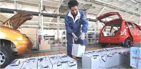  ??  ?? Preparing to install a lithium-ion battery on an electric car in an assembly line in China.