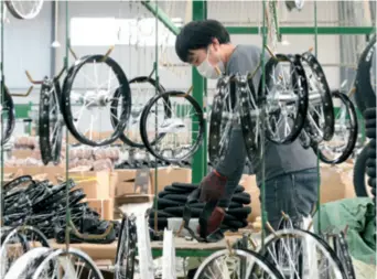  ??  ?? A worker is busy with work at a bicycle production line of a company in Wuhe County, Anhui Province, on March 11